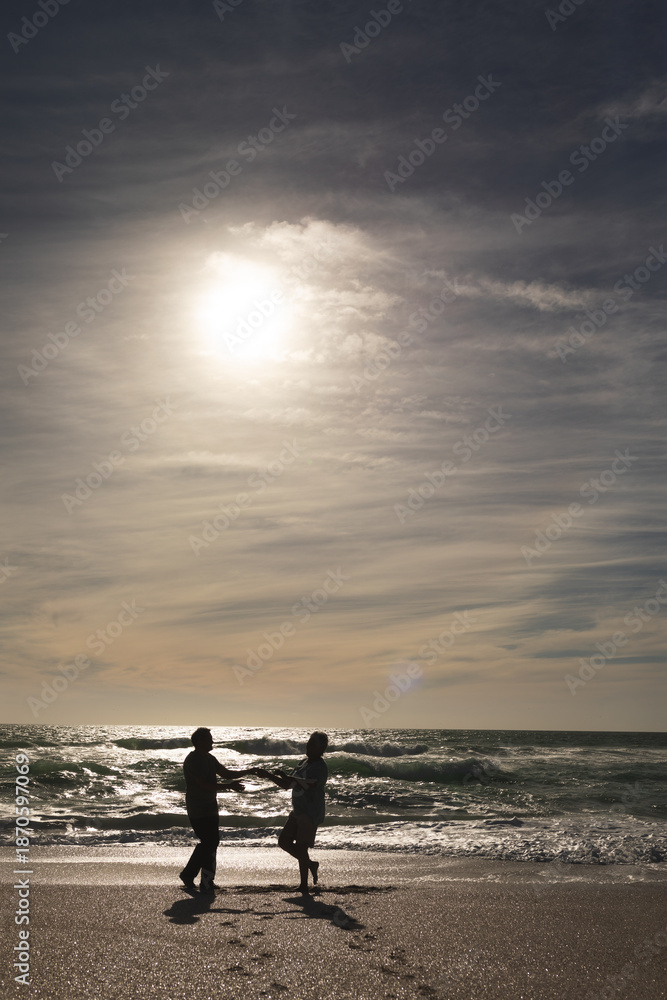 Naklejka premium Full length of multiracial senior couple dancing on shore at beach against sky during sunny day