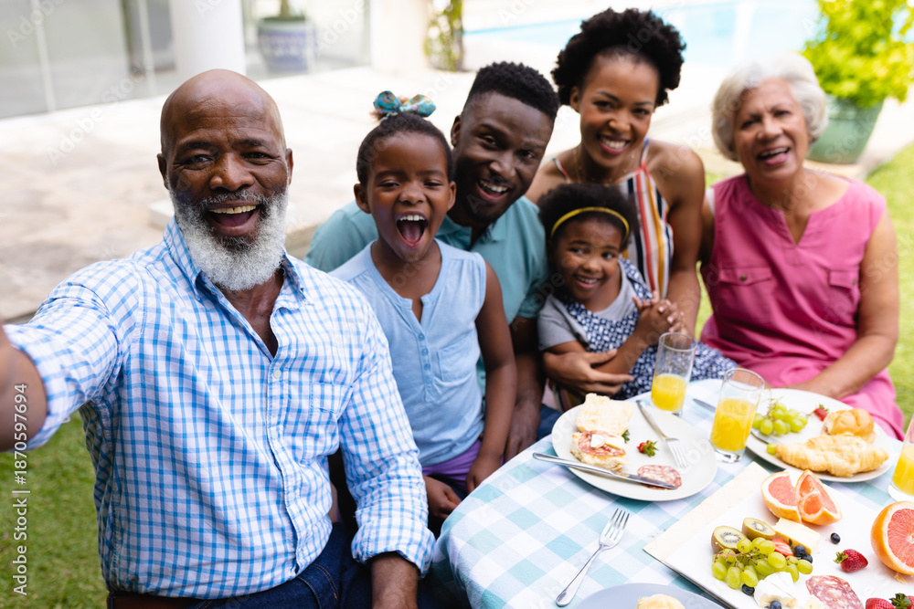 Obraz premium Portrait of cheerful african american three generational family taking selfie at brunch