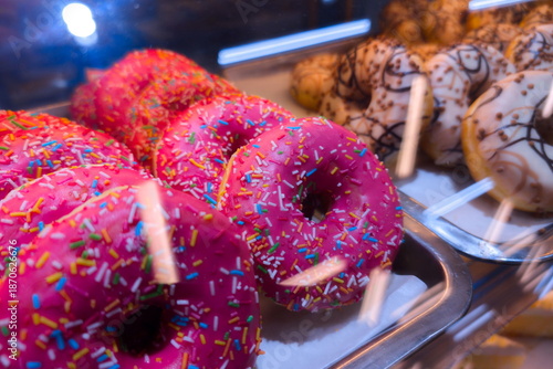 Schilderij op canvas Baked goods displayed in a shop with colorful donuts and sprinkles on top during