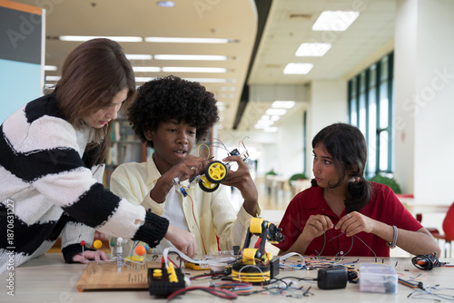 Fotografia Group of students learning to assemble robots in library room at school