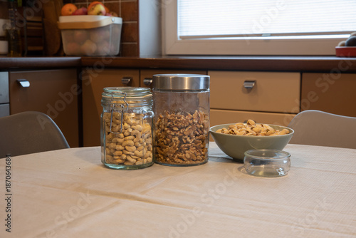 Nuts in jars on the kitchen counter. The bright, modern home decor showcases healthy snacks, including cashews, walnuts, and pistachios.