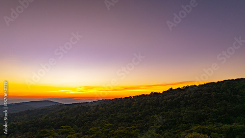 Foto A breathtaking sunset over layered mountain ranges, with warm golden light fading into a deep blue sky, creating a serene and expansive natural landscape ideal for travel and nature themes