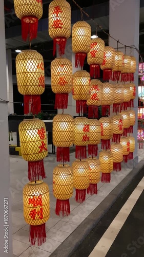 Warm, glowing bamboo Chinese lanterns with red tassels hanging in rows, creating festive and cozy atmosphere. Hainan, China. Traditional craftsmanship and ambient decorative lighting.