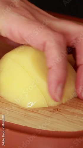 woman’s hands cutting peeled potatoes on a wooden cutting board