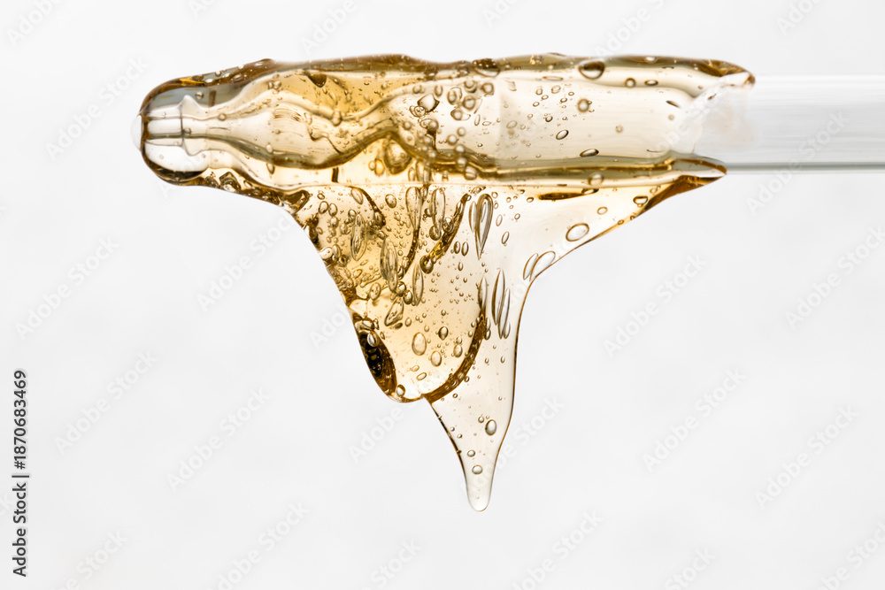 Naklejka premium Close-up of a pipette with yellow cosmetic texture flowing down.