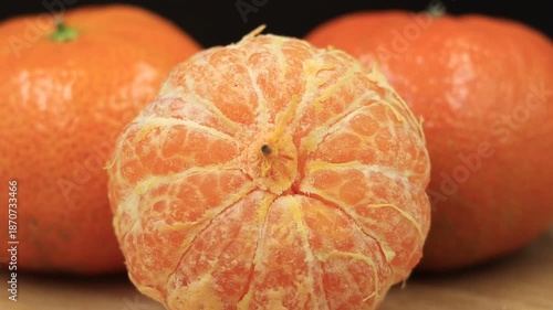 Partially peeled tangerine with other whole citrus fruits. Great for healthy food, cooking, or refreshing drink advertisements.