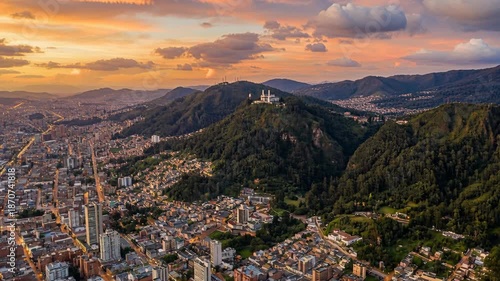 Vibrant Cityscape Panorama of Bogota Colombia at Golden Hour Dusk with Lush Green Monserrate Hillside and Dramatic Sunset Sky Above Dense