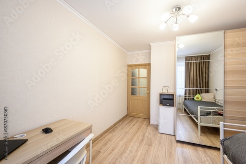 Wallpaper Mural A tidy bedroom with a mirrored wardrobe, single bed, wooden desk, frosted-glass door, small white cabinet, light wood flooring, and a ceiling light fixture. Minimalist style Torontodigital.ca