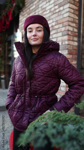 Portrait of woman in burgundy jacket and beret near Christmas greenery