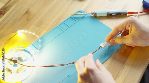 diy electronics Top view close-up of male hands connecting a USB Type-C cable to a soldered Type-C port on an LED strip, lighting up instantly on a silicone soldering mat. 