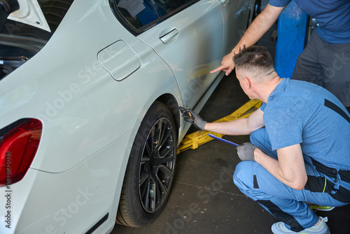 Adult mechanic inspects a car wheel on a lift