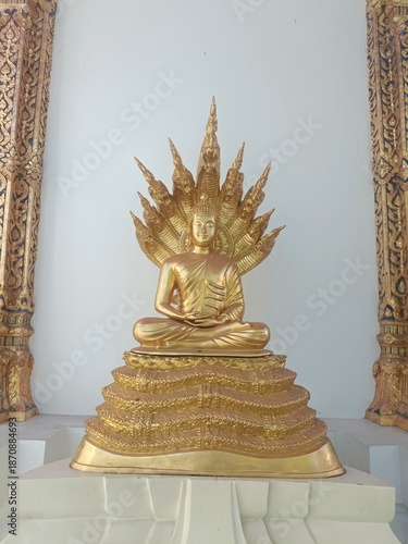 Fotografie Golden statue of a seated figure with elaborate headdress in a temple setting at
