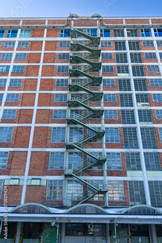Картината върху платно Old industrial building showing large brick facade with fire escape