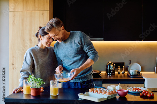 Foto Cheerful couple preparing a healthy breakfast with eggs, vegetables, and orange
