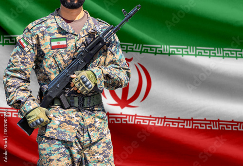 Iran flag with soldier in military uniform holding assault rifle in front of it