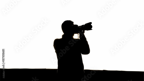 Silhouette of a photographer holding a professional camera and taking a photo.
