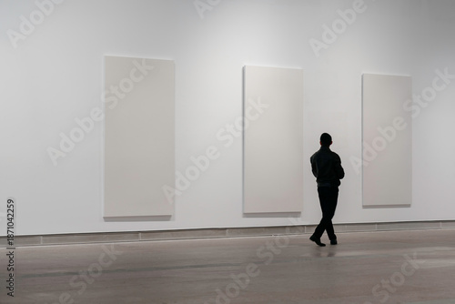 A man is looking at paintings in an art gallery.