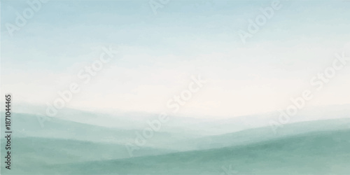 A breathtaking panorama of a misty mountain landscape at sunrise reveals soft clouds and fog drifting over the forest hills under a blue sky as the sun rises above the horizon