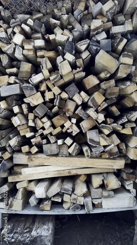 Winter background, chopped firewood stacked together and it is snowing,vertical video