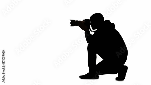 Silhouette of a photographer crouching and taking a photo.