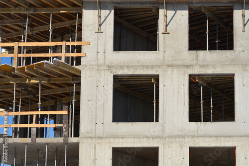 Cuadro en lienzo A concrete building facade under construction showing empty window frames and wooden scaffolding supports during a winter day