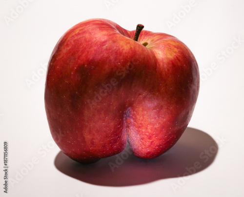 An ugly red apple. A fruit with a shape flaw on a white background.