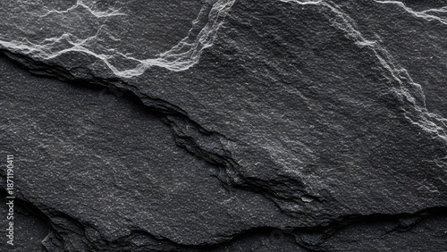 Extremely detailed close-up of natural black slate rock texture showing highly irregular layered surface structure sharp jagged edges and pronounced white crystalline mineral deposits