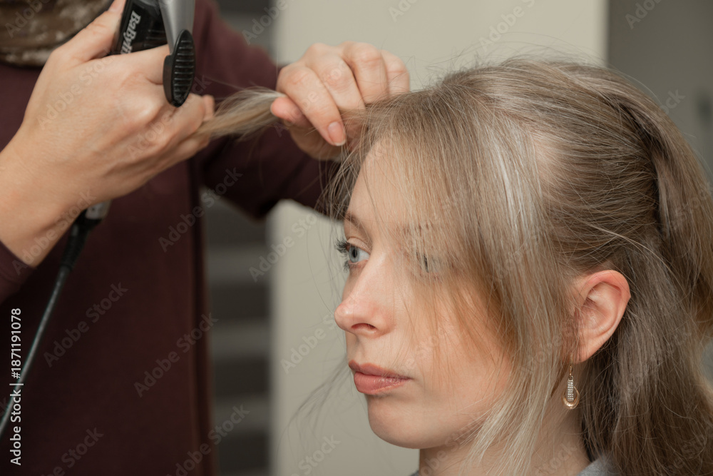 Fototapeta premium Hairdresser Curling Hair of Woman Using Styling Iron