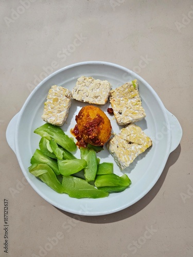 Tableau sur toile Steamed tempeh, boiled small chayote and eggs with balado chili sauce, served on a white plate, food for dieters