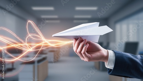 Close-up of hand in business suit holding white paper airplane with dynamic orange light streaks, symbolizing creativity, innovation, and new project launch in office setting
