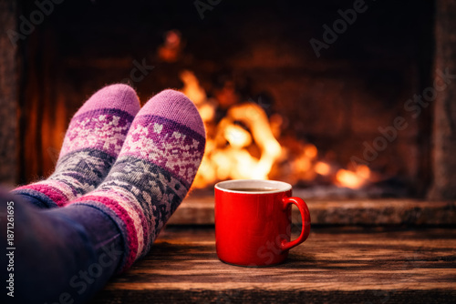 Cozy winter evening by the fireplace with warm knitted socks and a hot drink in a mug