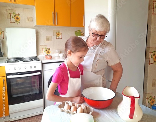 A grandmother and her granddaughter set out the necessary ingredients for cooking.