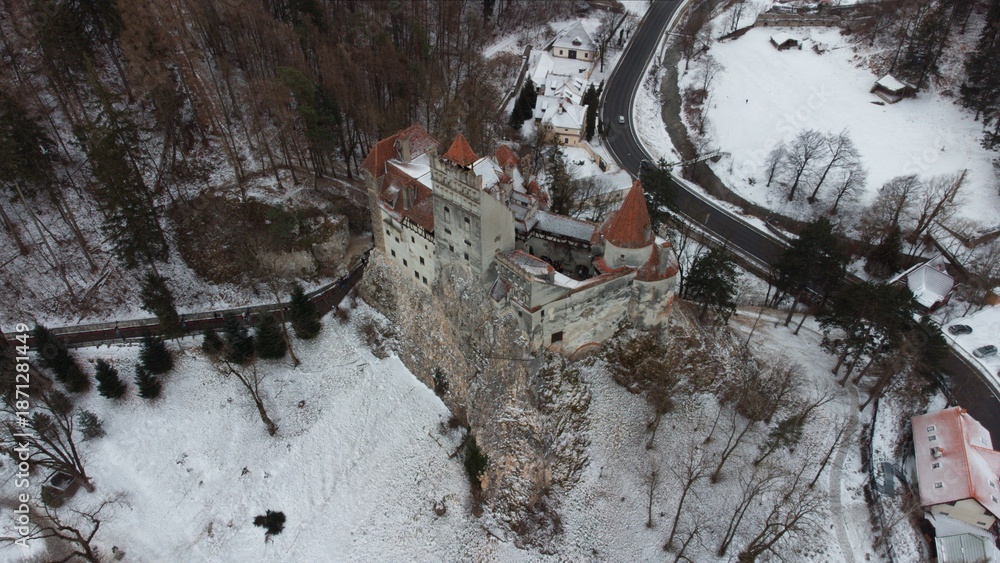 Obraz premium Aerial winter image of Bran Dracula Castle, the legendary Dracula fortress in Romania, drone view from above in fresh snow. The medieval Transylvania castle sits on a rocky hill. Travel background.