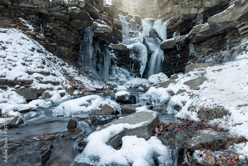 Frozen icy waterfall in the forest. Winter scenery.