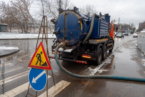 Reconstruction of the underground sewer system on a city street in winter. Road works. Water pumping with a special machine.