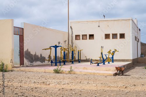 Outdoor old fitness area with kettlebells, tires, and gym equipment under cloudy sky in urban setting for active lifestyle concept, Africa, Cape Verde