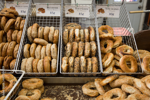 Assortment of bagels in a metal bin at a bagel shop.