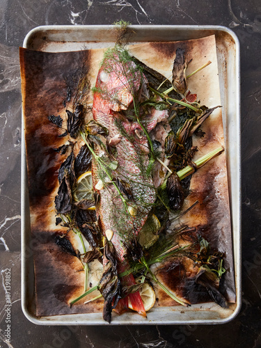 fresh baked fish on a metal tray, with herbs and spices.