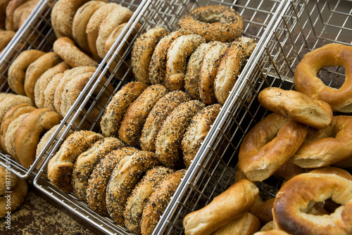 Assortment of bagels in a metal bin at a bagel shop.