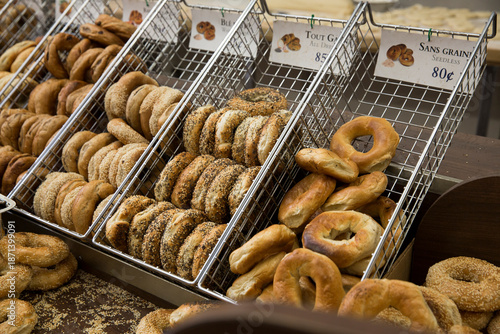 Assortment of bagels in a metal bin at a bagel shop.