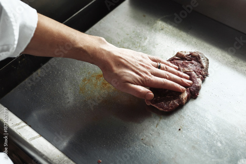 Chef expertly presses meat on hot griddle to create savory crispy crust