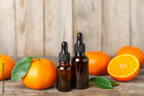 Tangerine essential oil on a wooden table. Bottles of citrus essential oil and sliced ​​fruits. Fragrant tangerine oil with tangerines. Cosmetic oil for spa treatments. Aromatherapy concept. 