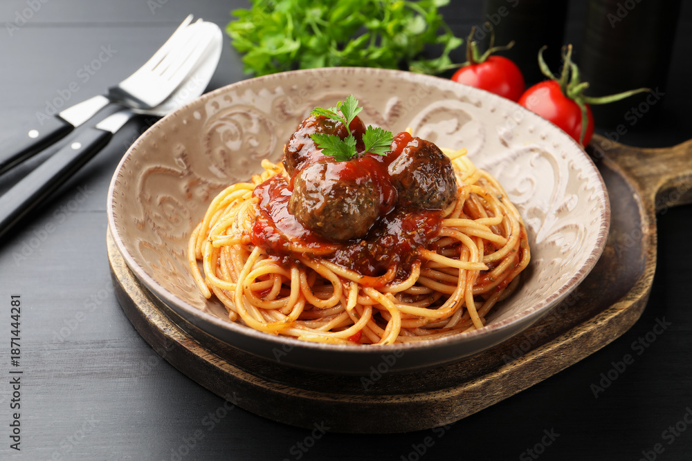 Fototapeta premium Delicious pasta with meatballs served on black wooden table, closeup