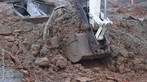 excavator bucket digging mud and gravel fill
