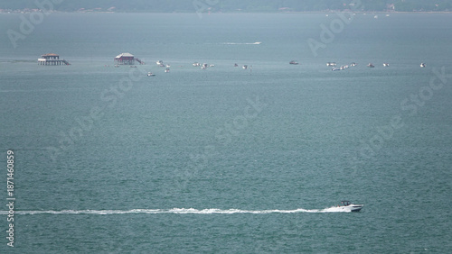 Bateau à moteur rapide laissant un sillage avec vue sur les Cabanes Tchanquées du Bassin d'Arcachon