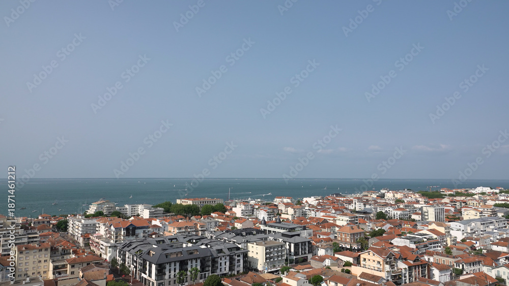Naklejka premium Vue panoramique aérienne de la ville côtière d'Arcachon avec toits rouges et l'océan à l'horizon