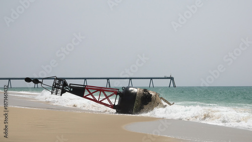 Grande bouée de navigation maritime rouge et noire échouée sur une plage de sable