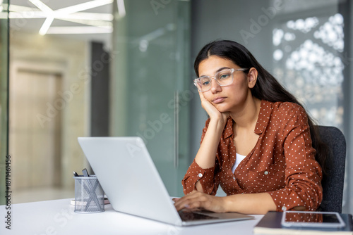 Foto Young indian woman experiencing job stress and boredom, resting her head on her