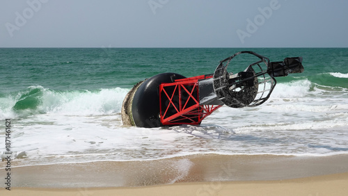 Grande bouée de navigation maritime rouge et noire échouée sur une plage de sable