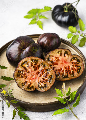 Φωτογραφία Sliced Marsha’s Starfighter Beefsteak tomatoes (Solanum lycopersicum) on a ceramic plate with leaves and stems